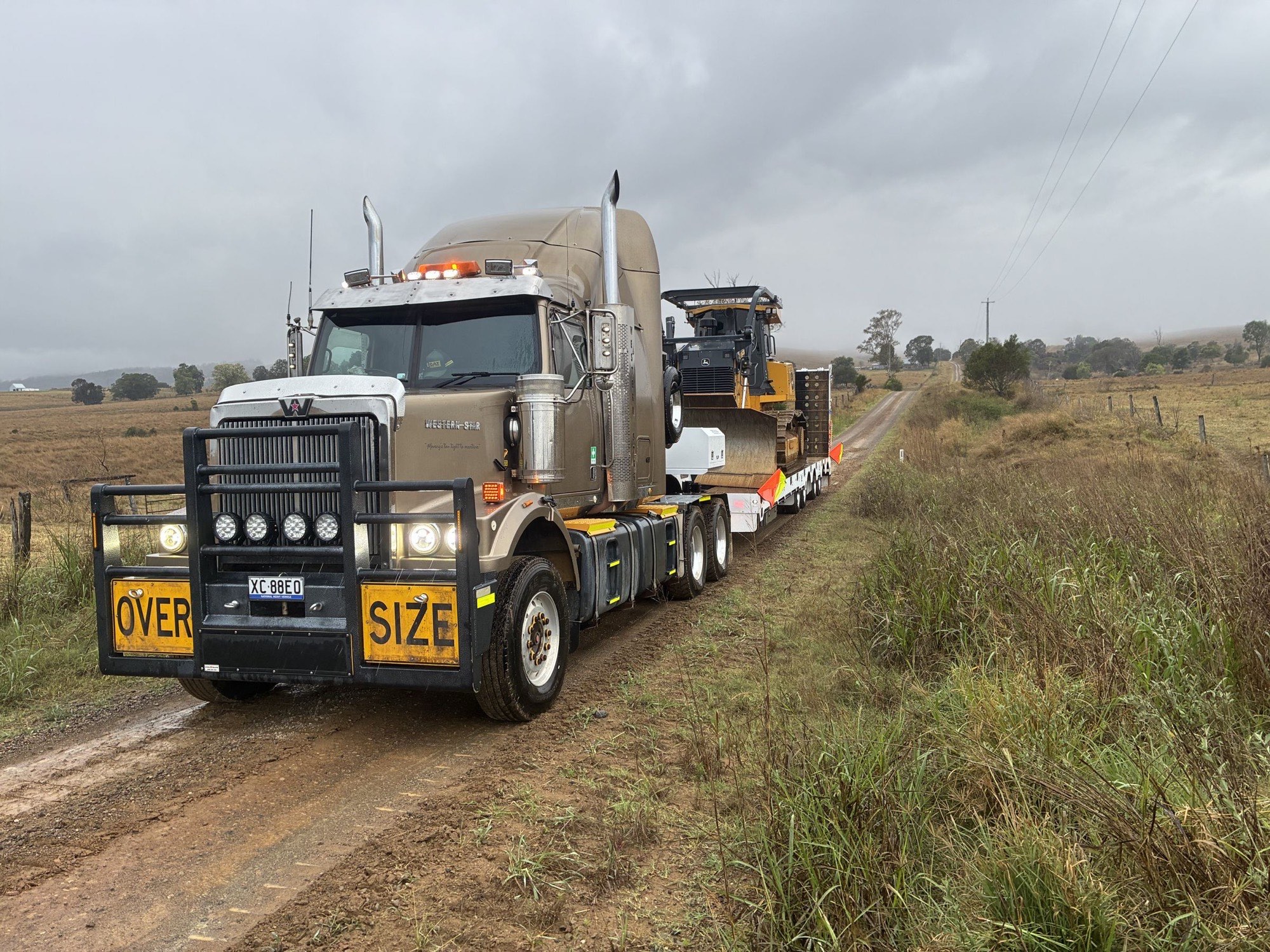 Western Star towing a dozer on the float along a wet country road